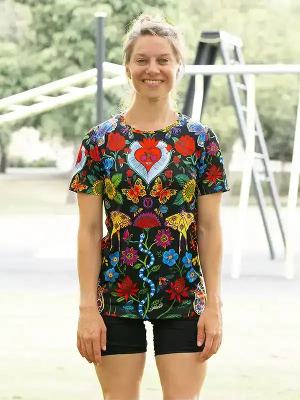 Woman wearing colorful floral cycling jersey with heart design, paired with black shorts, outdoors