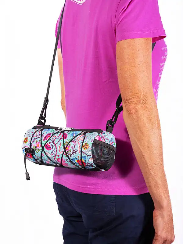 Person wearing a colorful crossbody bike bag with a white background
