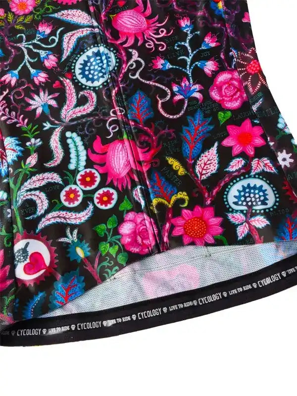 Vibrant floral cycling jersey with bold pink, blue, and green patterns on black fabric, featuring brand trim