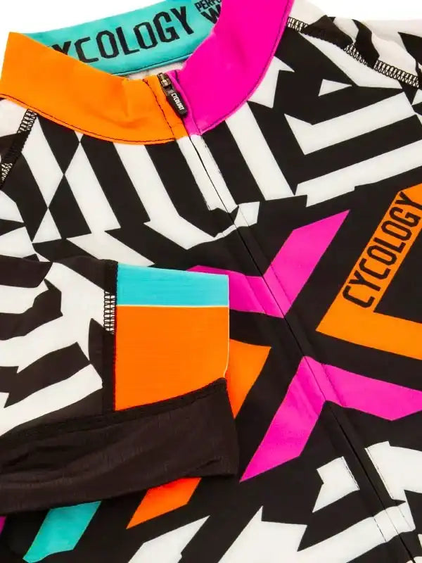 Vibrant geometric cycling jersey with bold black, white, pink, orange, and teal accents for men and women.