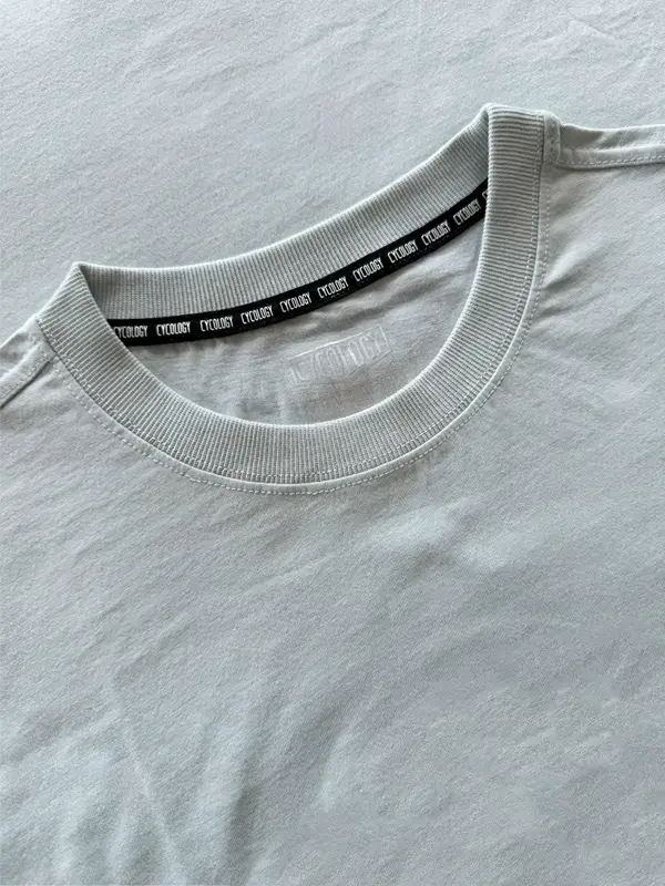 Close-up of a gray t-shirt with a black label on the collar against a light gray background