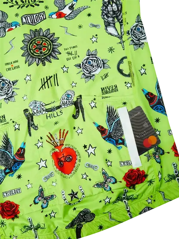 Vibrant green cycling shorts with tattoo-style graphics, roses, birds, stars, and motivational phrases for road or mountain biking.