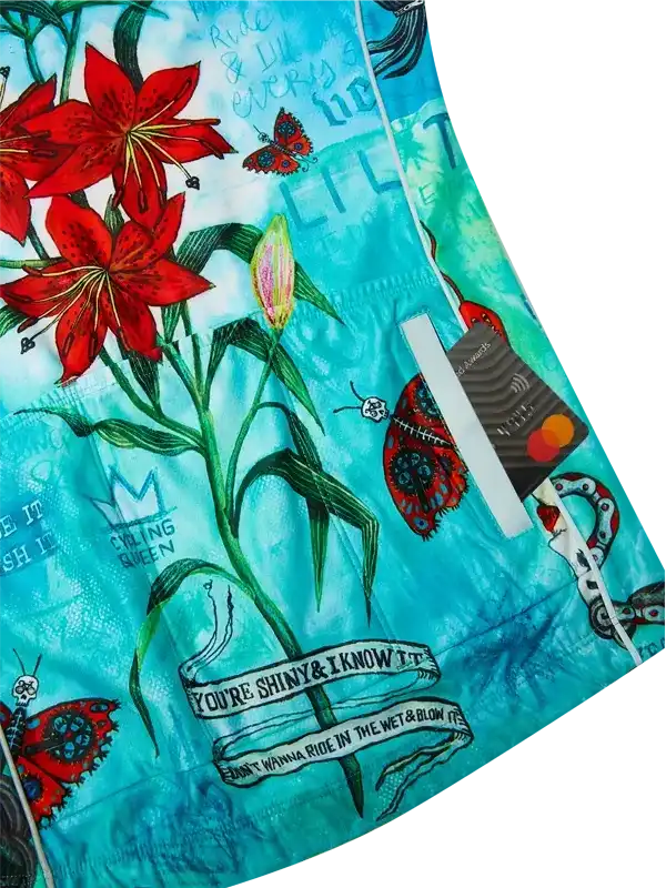 Vibrant turquoise cycling shorts with red lilies, butterflies, and bold text designs for women's bike wear.