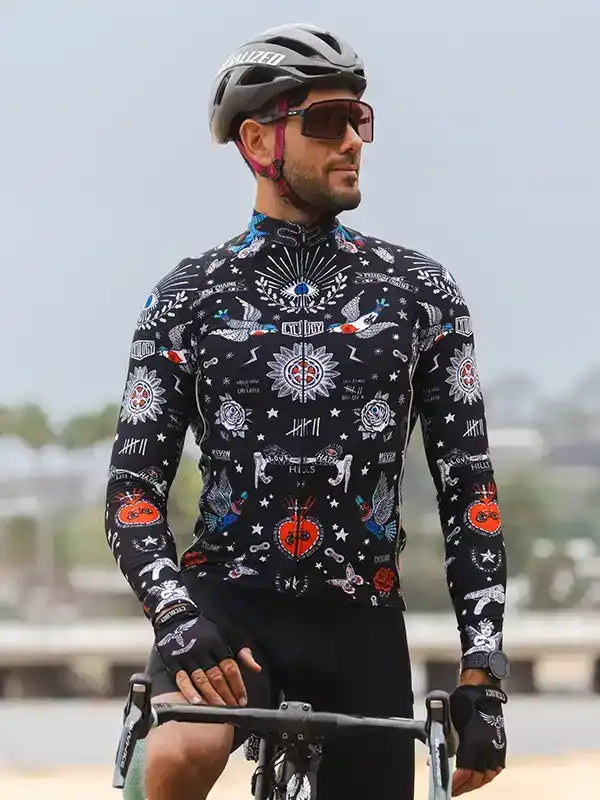 Man cycling in black long-sleeve jersey with tattoo-style graphics, helmet, and sunglasses