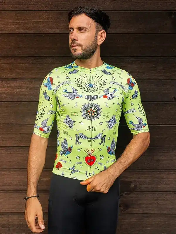 Men's neon green cycling jersey with tattoo-style bird and heart print, worn with black bib shorts