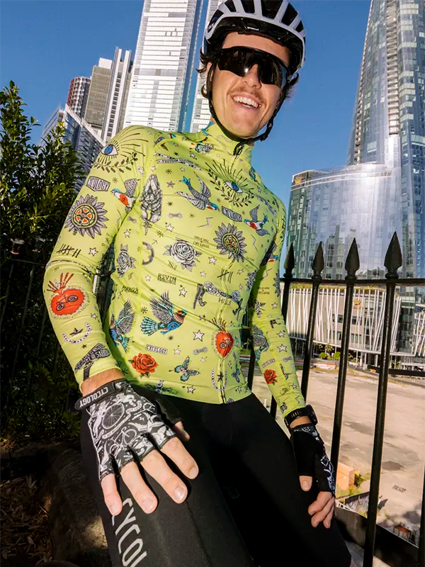 Person wearing a colorful lime green cycling jersey with tattoos in an urban setting