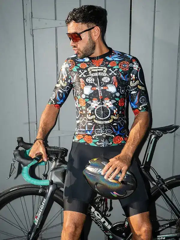 Man in colorful cycling jersey and shorts holding helmet beside road bike, stylish men's cycling apparel