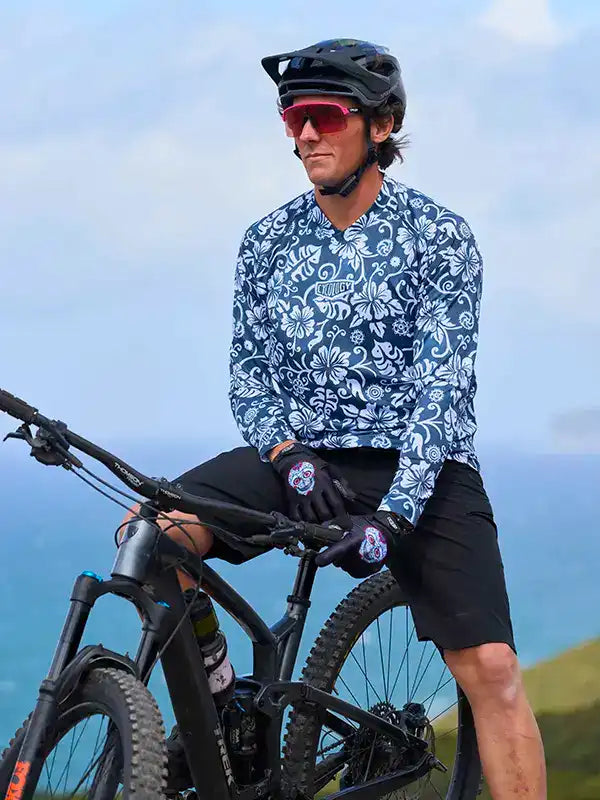 Man in floral cycling jersey and helmet on mountain bike, coastal view background