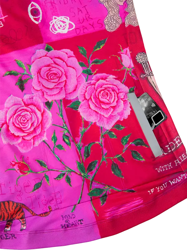 Close-up of a vibrant fabric with pink roses, green leaves, and text on a red background.