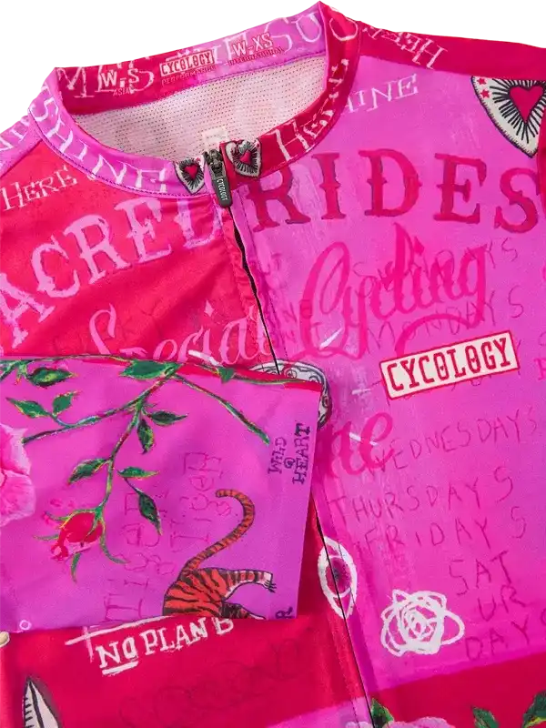 Pink women's cycling jersey with 'Sacred Rides' print, floral and tiger graphics, and Cycology branding
