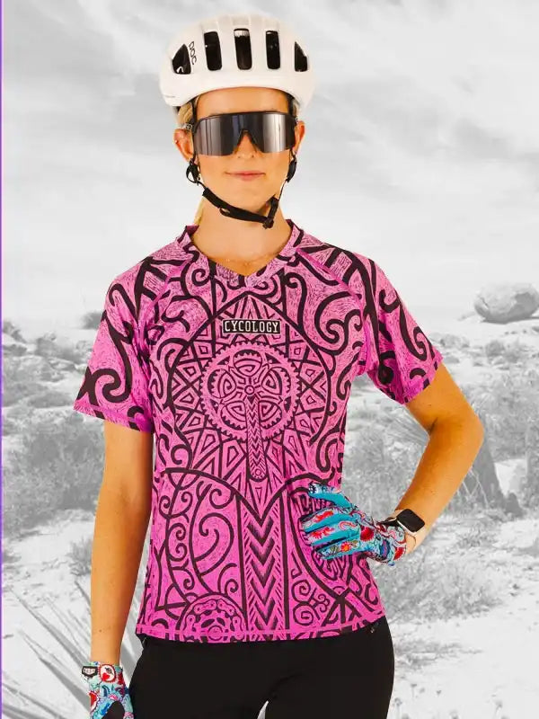 Woman in pink patterned cycling jersey, helmet, and sunglasses, ready for a ride