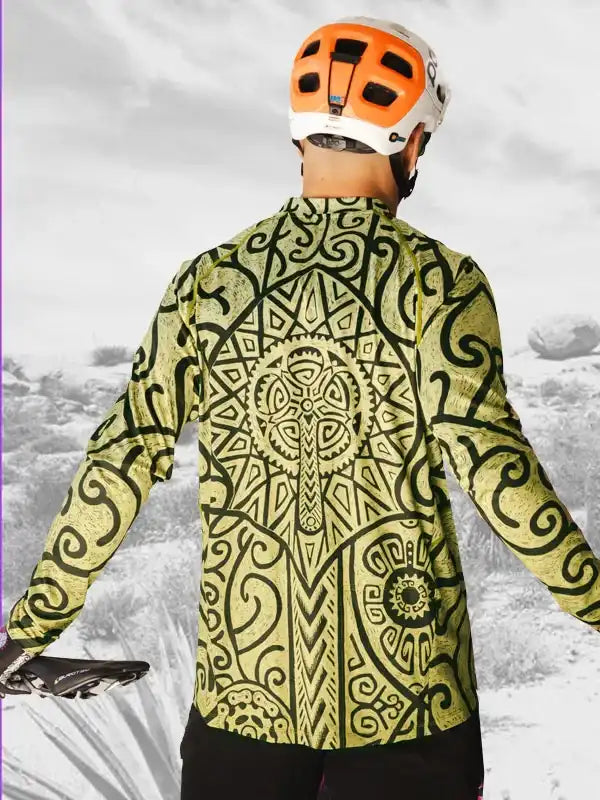 Men's cycling jersey with bold Maori-inspired print, long sleeves, worn with helmet on trail