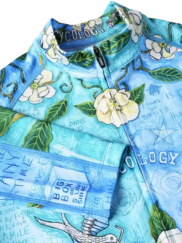 Blue floral women's cycling jersey with white flowers, green leaves, and inspirational text, featuring full zip and performance fabric.
