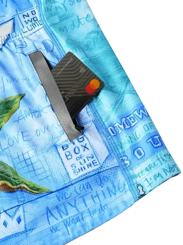 Blue cycling shorts with pocket holding credit card, featuring artistic text and leaf print design