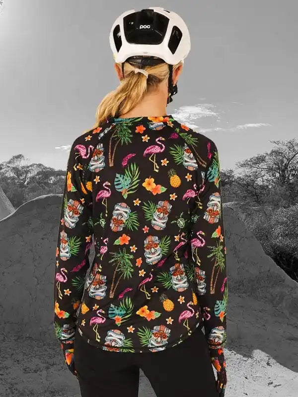 Women's tropical print cycling jersey with flamingos, pineapples, and tiki masks, worn with white helmet