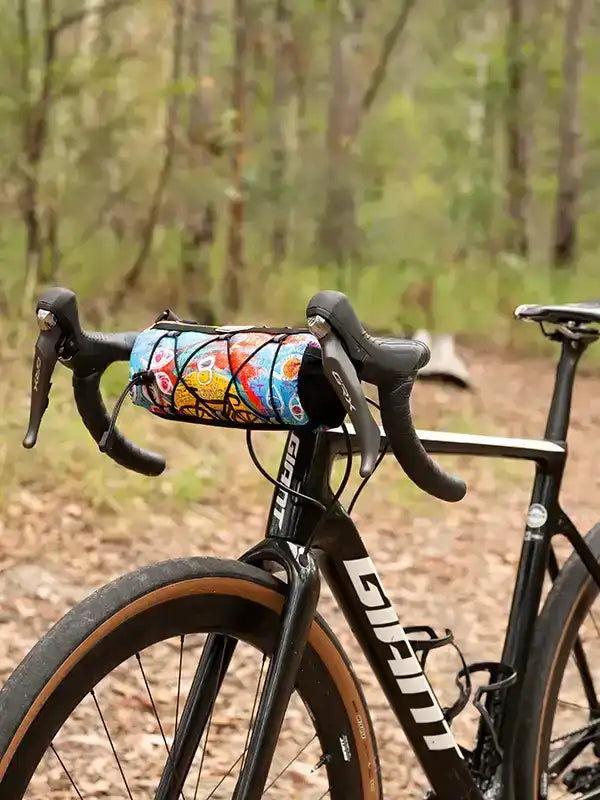 Colorful cycling frame bag on road bike handlebars, perfect for bikepacking adventures in nature.