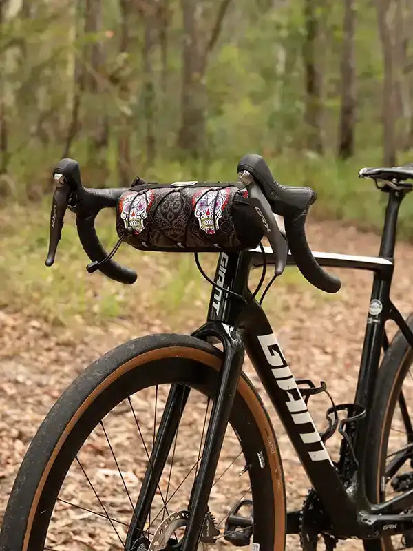 Cycling handlebar bag with sugar skull print on road bike in forest trail