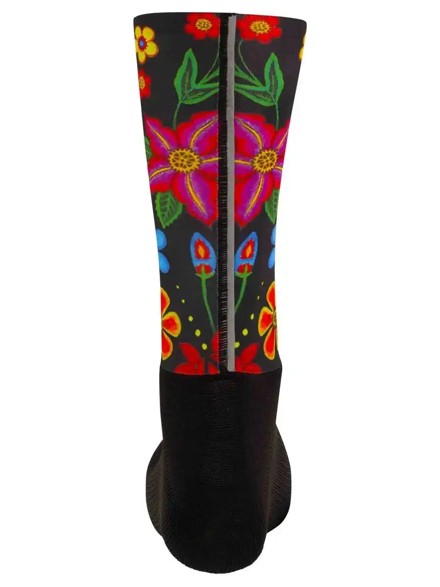 Colorful floral cycling sock with vibrant pink, red, and blue flowers on black background, featuring reflective strip for safety.