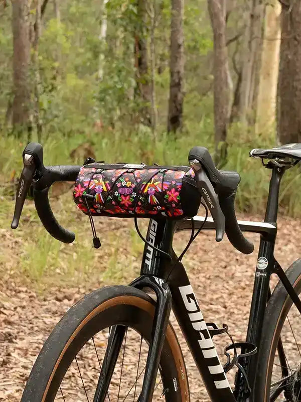 Floral bike frame bag on black road bike in forest trail, cycling gear for outdoor rides