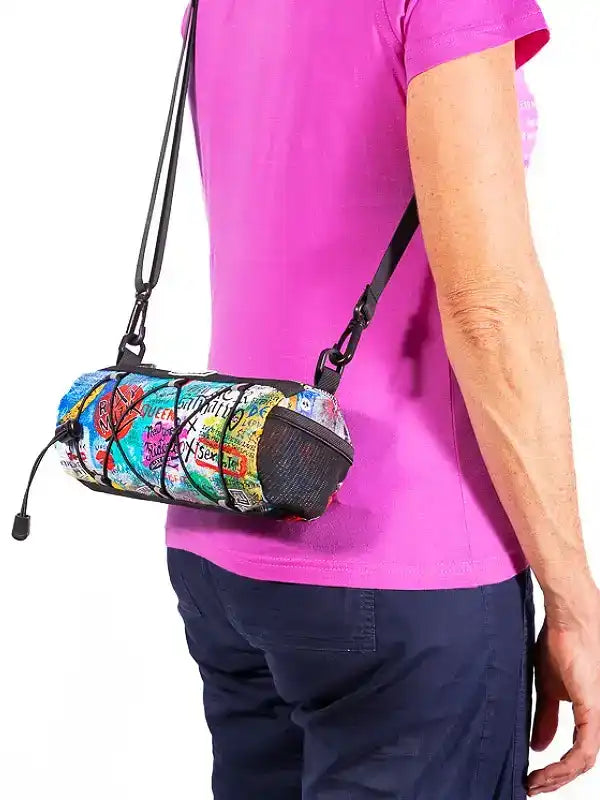Colorful graffiti-print cycling waist bag with mesh pocket, worn crossbody by woman in pink tee