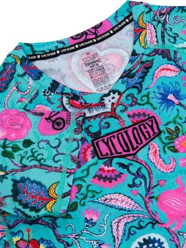Vibrant turquoise cycling jersey with pink floral and bike graphics, featuring 'CYCOLOGY' logo and performance fabric tag