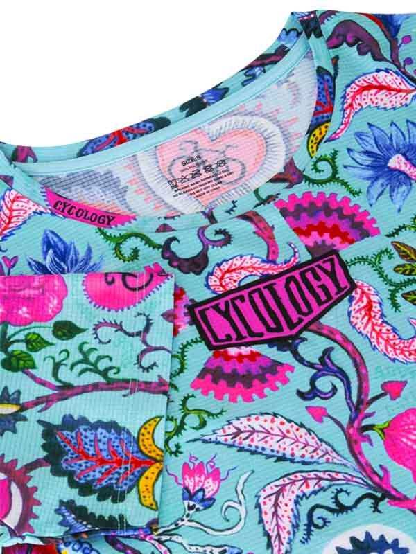 Vibrant floral cycling jersey with bold pink 'CYCOLOGY' logo, ideal for women's bike wear