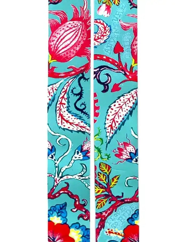 Vibrant tropical print cycling arm warmers with bold floral and leaf patterns on teal background