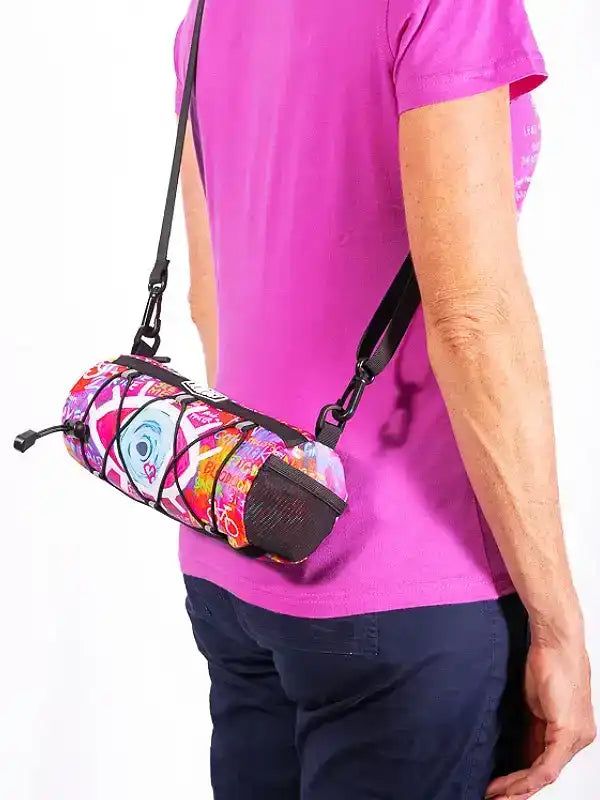 Colorful cycling waist bag with vibrant print, worn crossbody by person in pink shirt