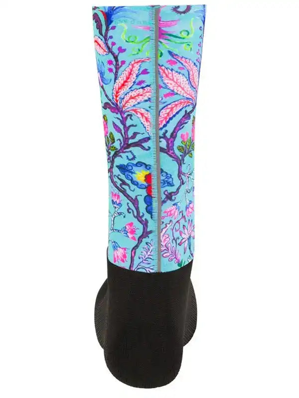 Colorful floral cycling arm sleeve with vibrant leaf pattern on light blue background, black compression base