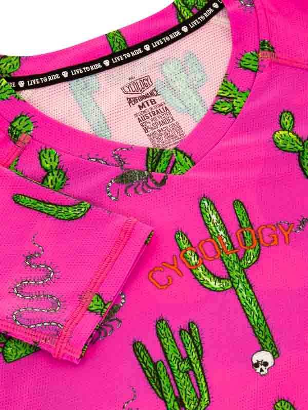 Pink cycling jersey with cactus, snake, and skull print, featuring 'LIVE TO RIDE' neck tape and breathable fabric.