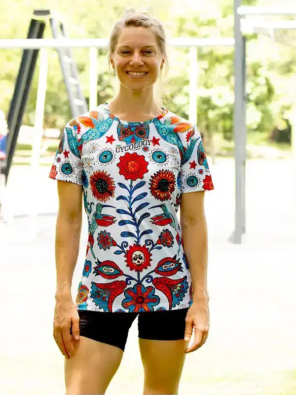 Woman wearing colorful floral cycling jersey with 'Cycology' logo, ideal for bike rides and outdoor fitness.