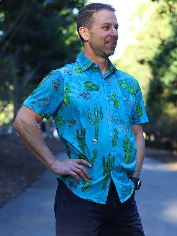 Man wearing vibrant blue cactus-print cycling shirt outdoors, ideal for casual rides and warm weather.