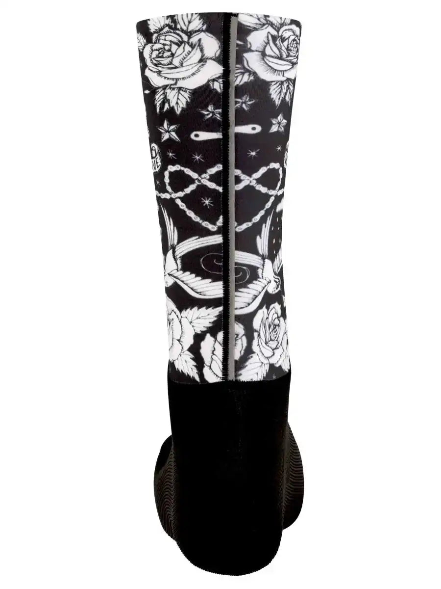 Black cycling sock with white rose, chain, and star tattoo-style print, ideal for men's and women's bike rides