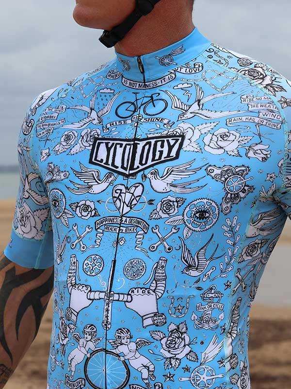 Men's light blue cycling jersey with tattoo-style graphics, roses, birds, and bike motifs for road cycling