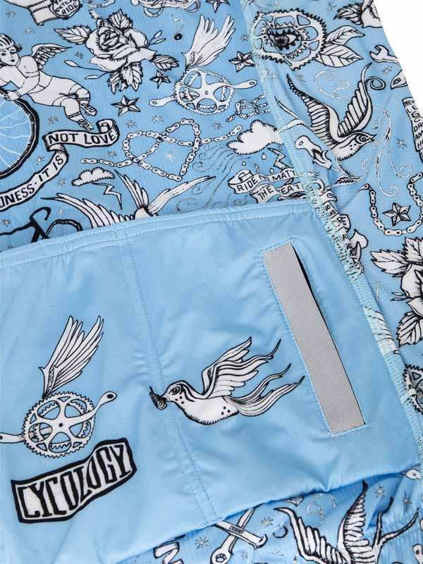 Light blue cycling shorts with tattoo-style bird, gear, and rose print, reflective strip, and pocket detail