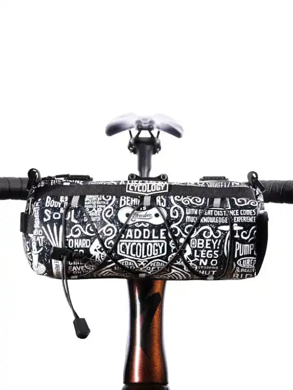 Black and white patterned cycling handlebar bag with bold text designs, mounted on bike handlebars