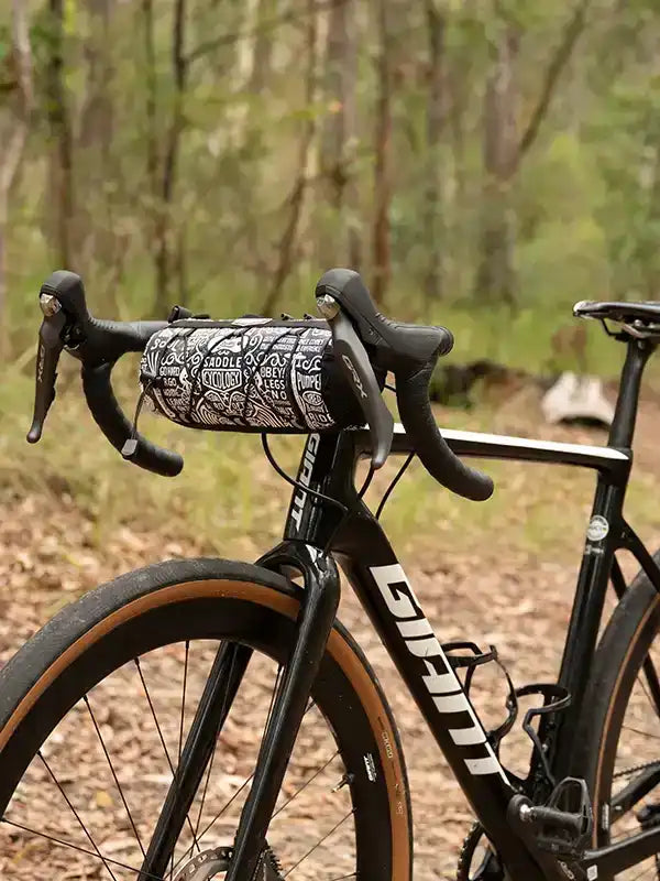 Cycling handlebar bag with doodle print on black road bike in forest setting